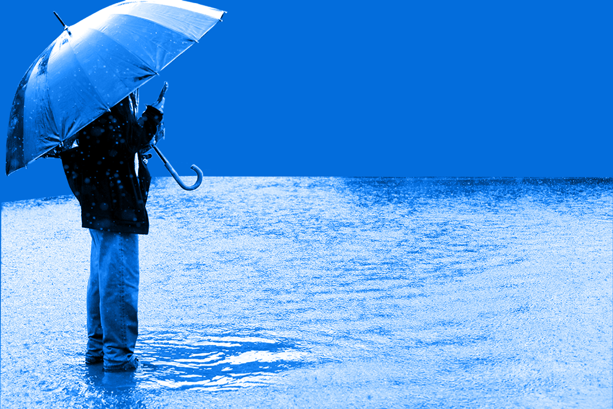 Person holding umbrella in very large puddle.