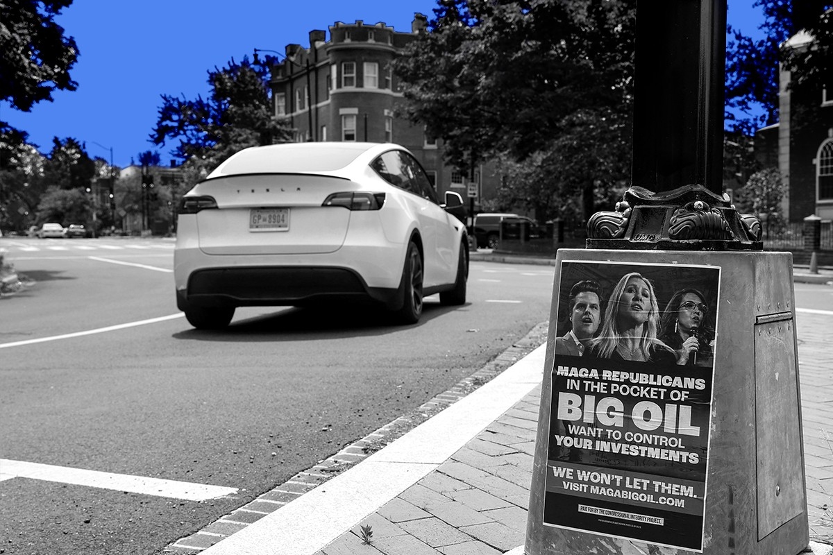 A Tesla driving past a political sign.