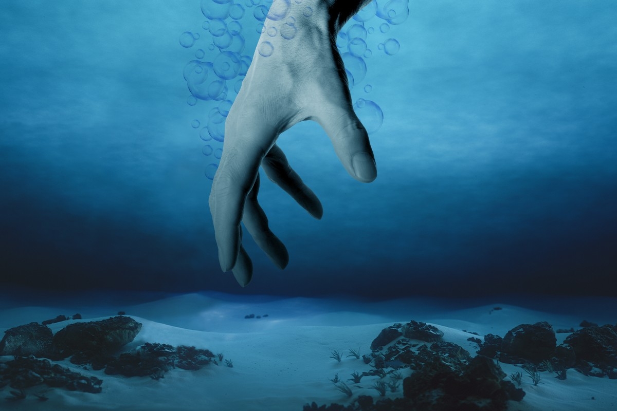 A hand reaching into deep water.