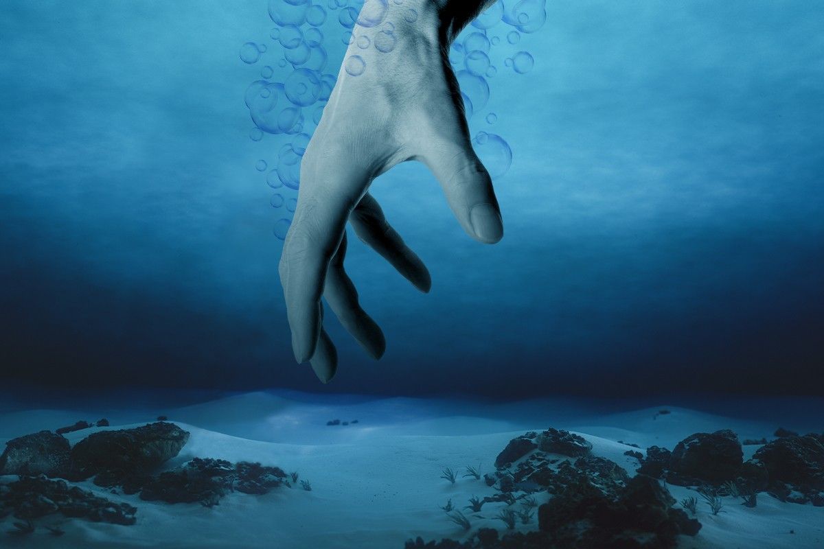 A hand reaching into deep water.