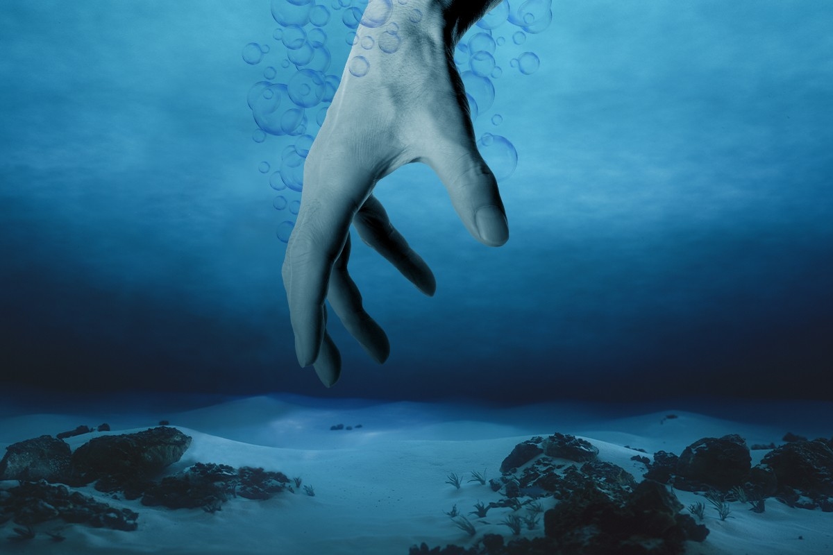 A hand reaching into deep water.
