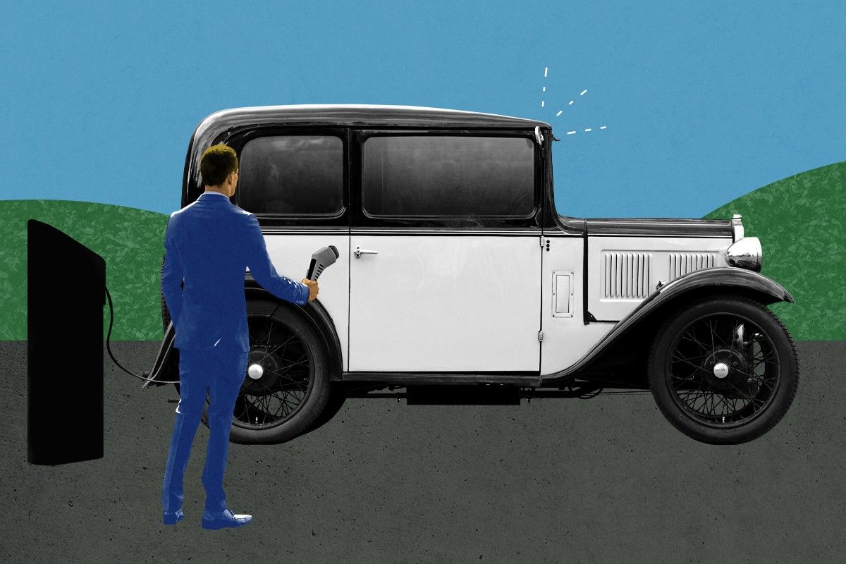 A man charging a very old car.