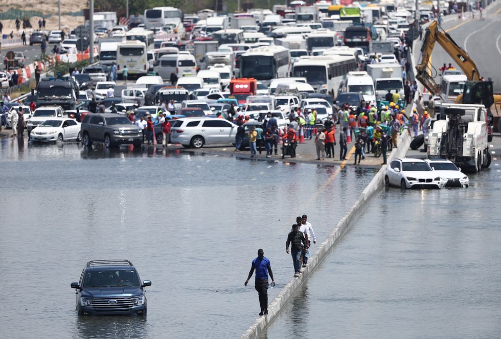 People walk along an flooded highway on April 18, 2024 in Dubai, United Arab Emirates. 