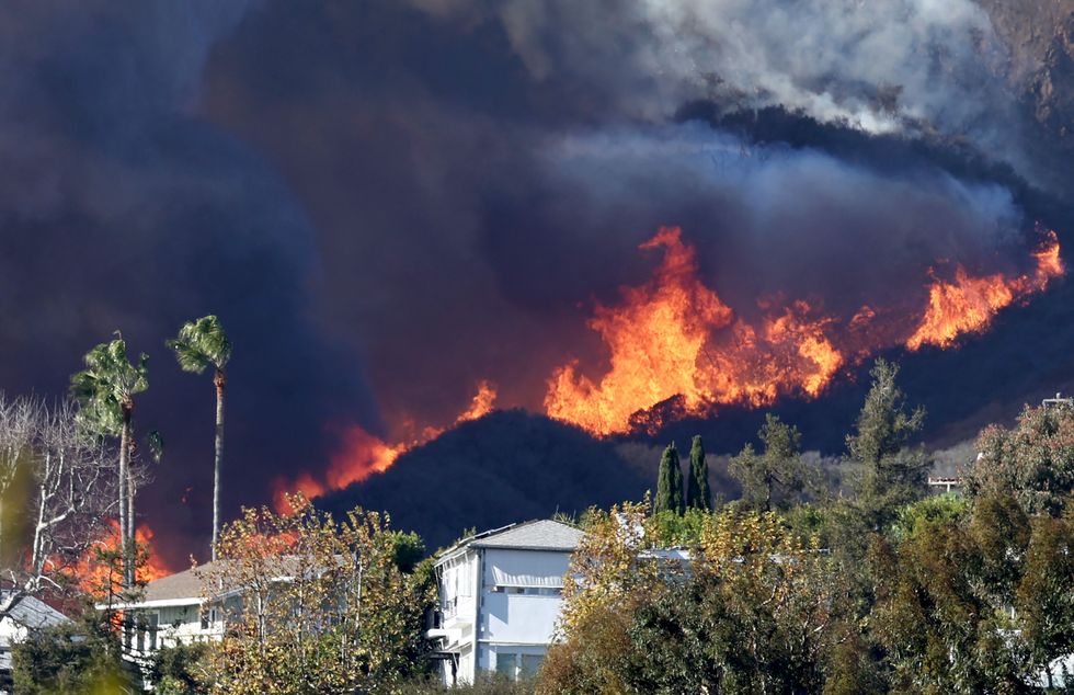 The Palisades Fire burns near homes amid a powerful windstorm.