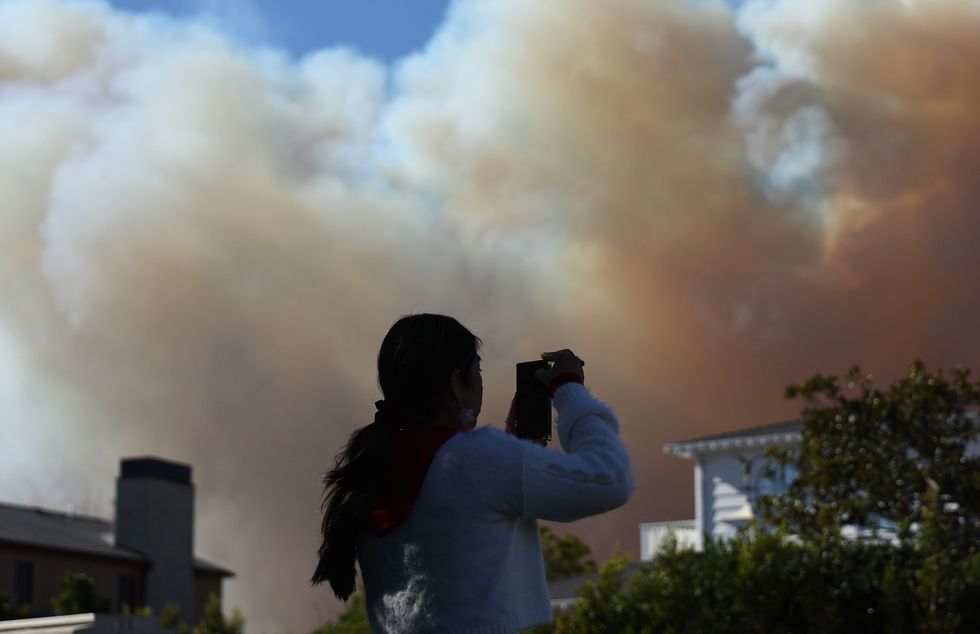 An onlooker takes photos as the Palisades Fire burns.