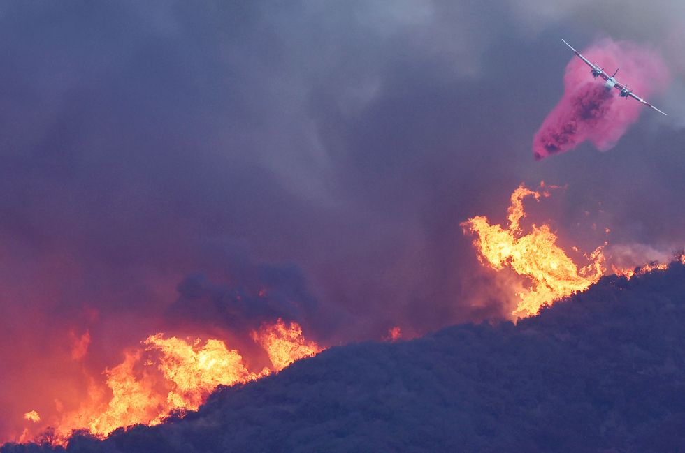 A firefighting aircraft drops a fire retardant on the Palisades Fire Tuesday.
