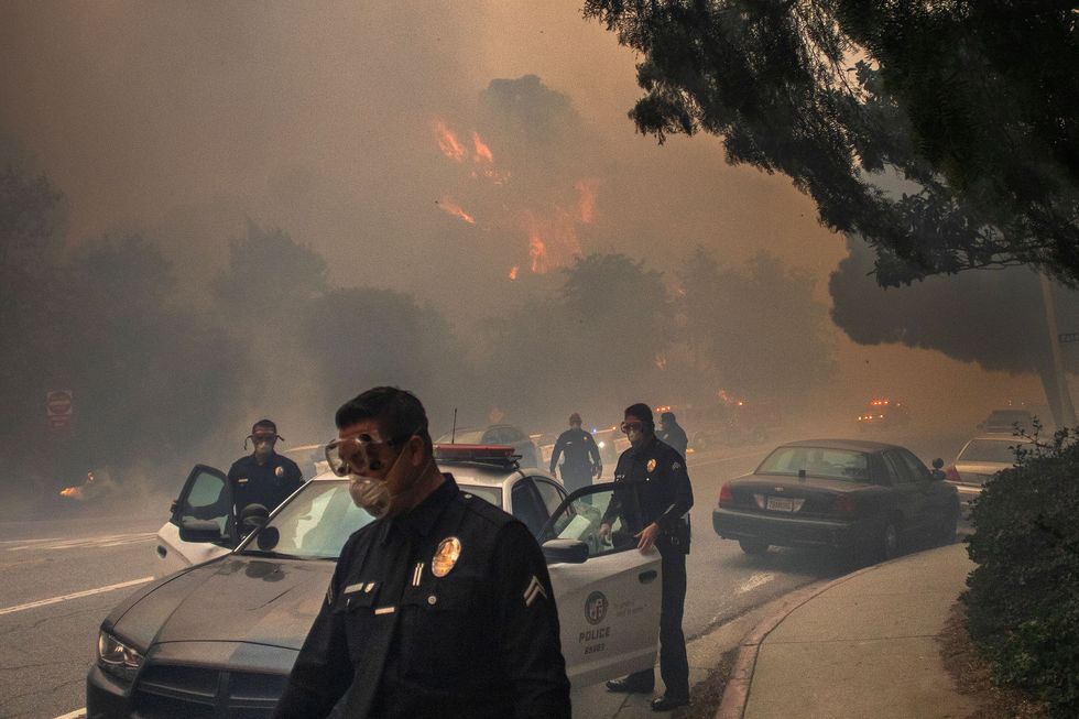 Police officers help people evacuate along Sunset Boulevard.