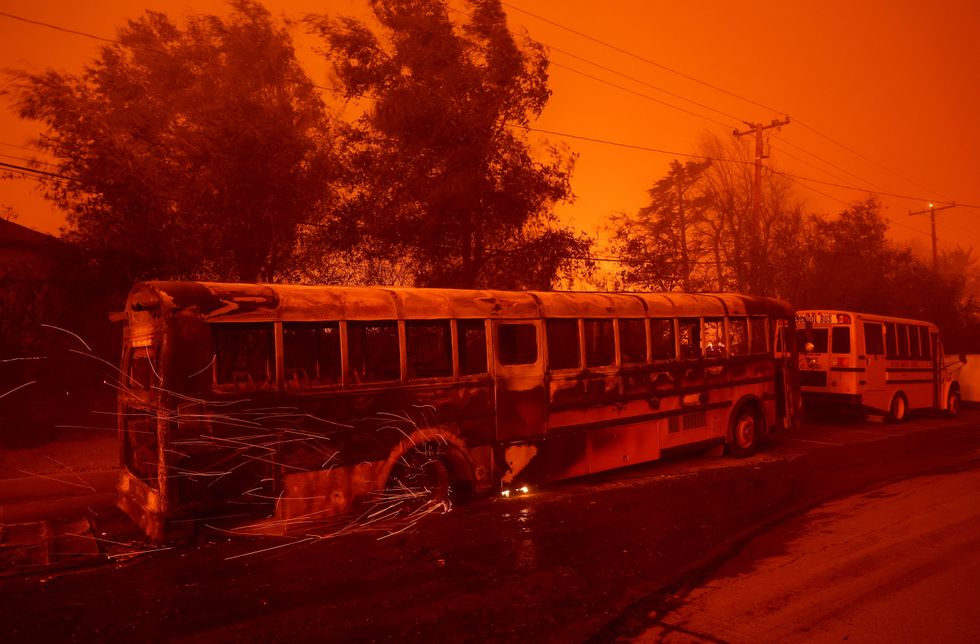 Sparks fly from the wheel of a burned school bus as the Eaton Fire moves through Altadena on Wednesday morning.