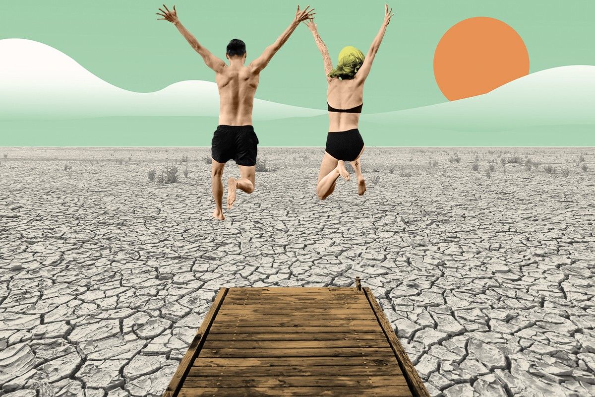 A couple jumping into a dry river.