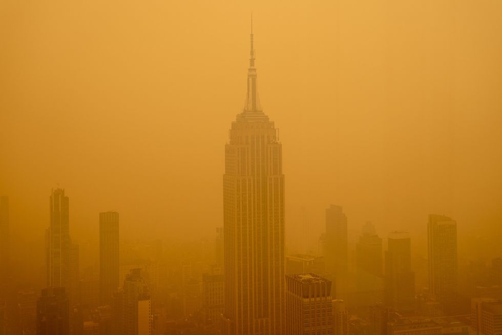 The Empire State Building in New York City obscured by smoke against an orange sky