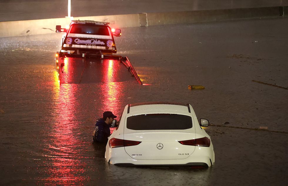 A tow truck driver attempting to pull a stranded car out of floodwaters.