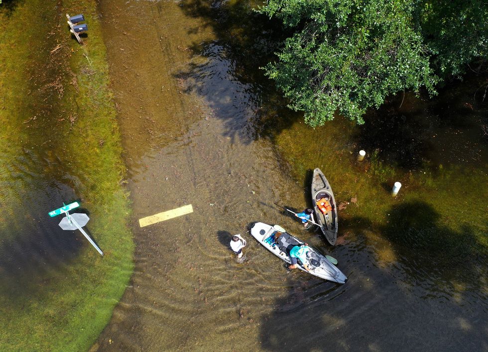 People kayaking through flooded streets.